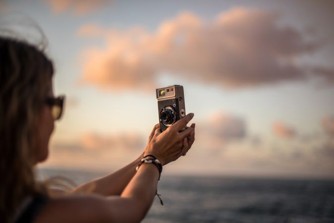 Creative woman taking photo on camera in sunny day