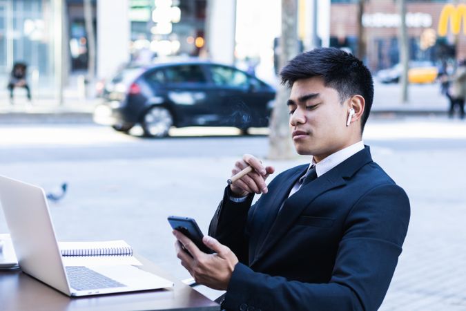 Businessman smoking cigar in street cafe