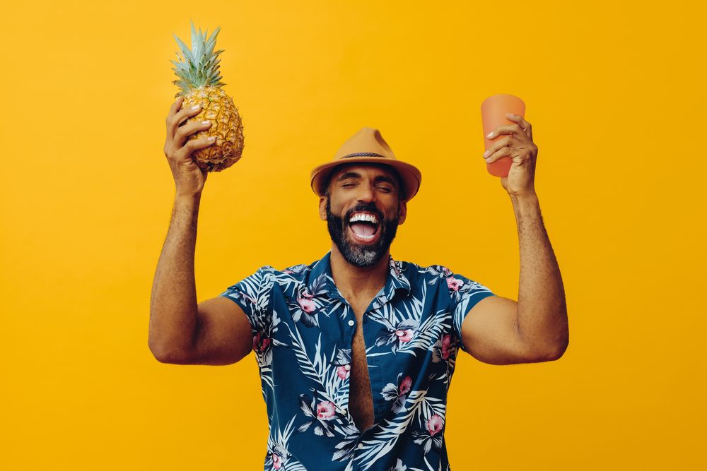 Jubilant male holding up a pineapple and orange cup