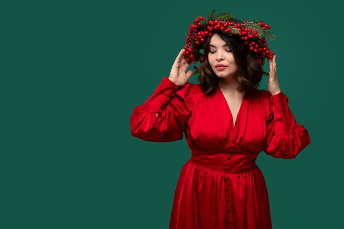 Woman in red dress with berry wreath posing elegantly