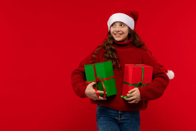 Girl in Santa hat holds Christmas presents