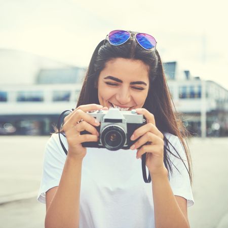 Smiling woman with sunglasses on her head taking pictures