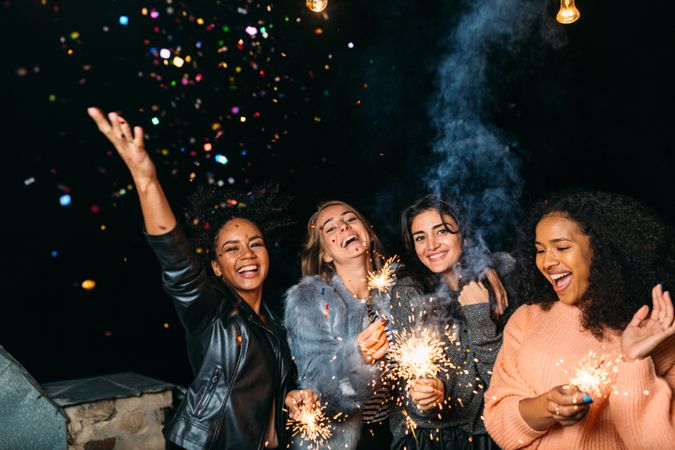 Multi-ethnic group of fun women celebrating at a party with sparklers