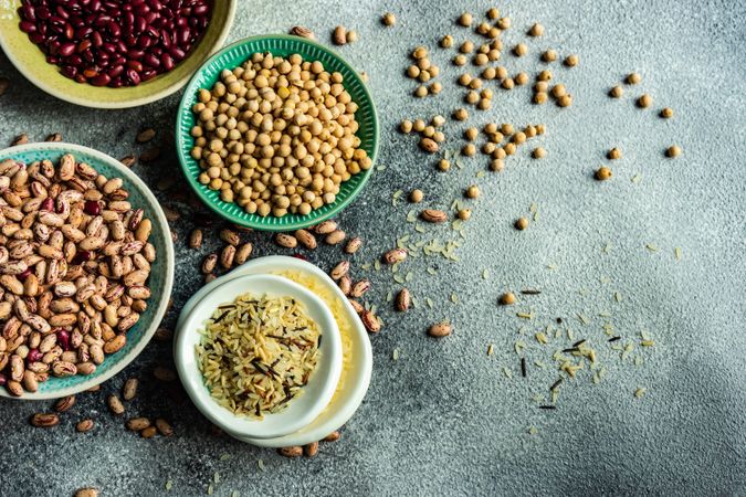 Top view of bowls of dried grains and legumes from pantry with copy space