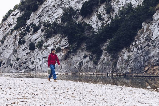Woman with case walking on shore above stream
