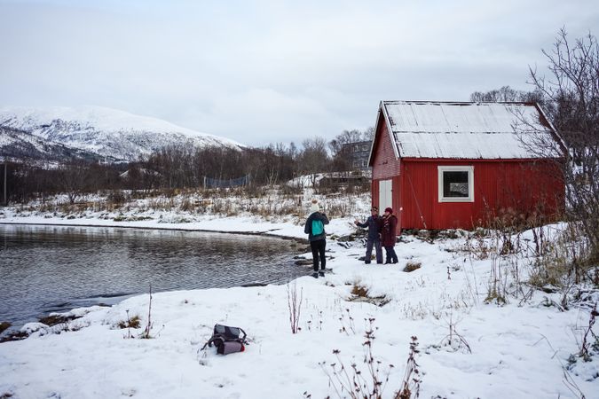 Friends talking on coast against snowy highland in cold wintry day