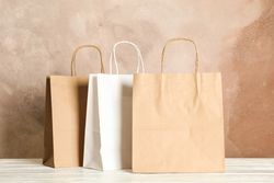 Paper bags on table against brown background, copy space