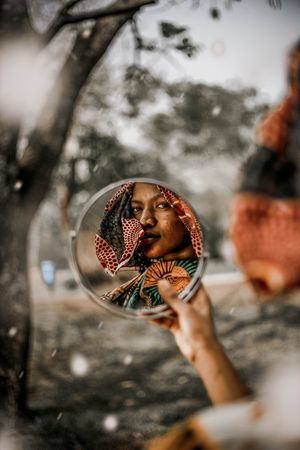 Woman in brown scarf holding round mirror
