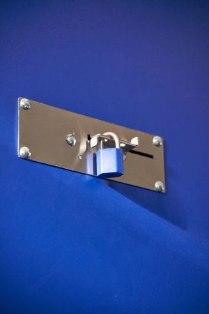 A blue locked lock on a metal barrier in a storeroom