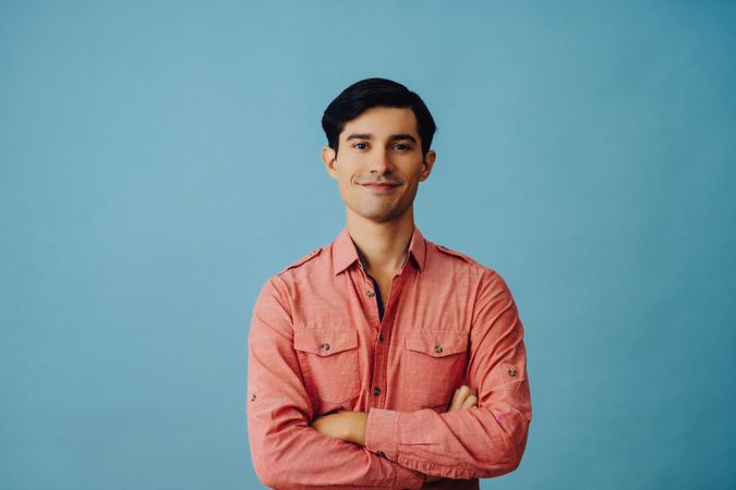 Mid portrait of confident Hispanic male looking at camera with arms crossed