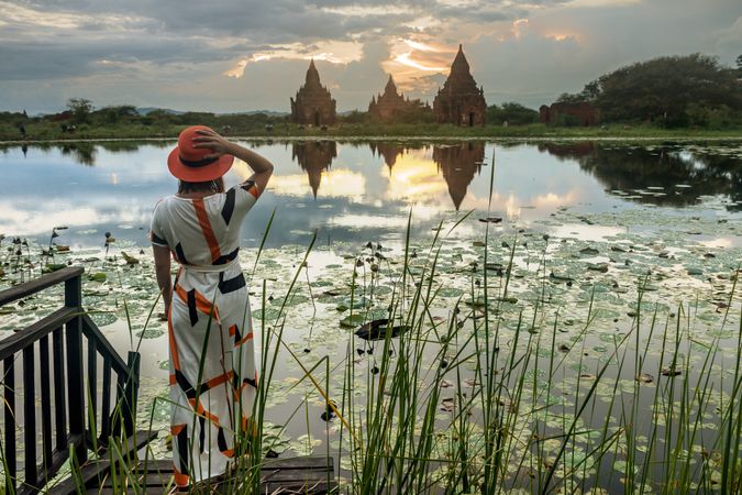 Woman standing at lakeside and enjoying view of Buddhist temples