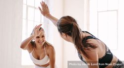 Smiling fitness women raise hands to give a high five during workout bGnqv4