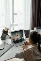 Back view of young girl attending an online class