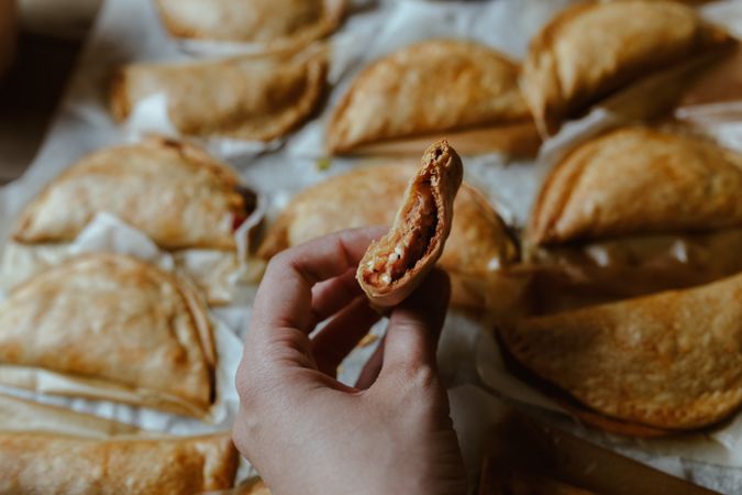 hand holding and Baking tray with composed freshly baked pies patty