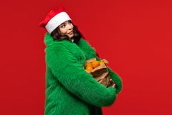 Woman in Santa hat and green coat holds oranges