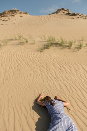 Young woman lying down on sand dune