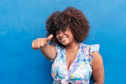 Black woman smiling with blue background.