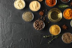 Glass bowls full of spices arranged on dark table with copy space
