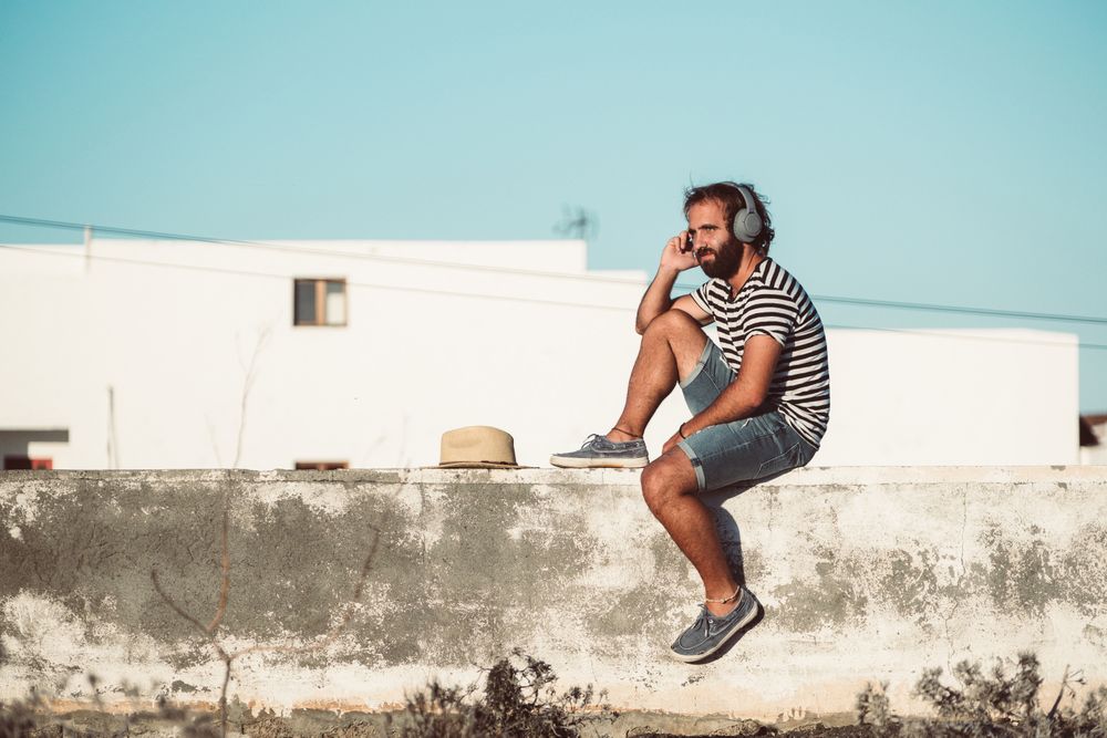 Young male sitting with smartphone and headphones