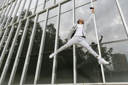 Enthusiastic Black man jumping raising hand like superhero