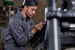 Focused technician repairing motorcycle in workshop