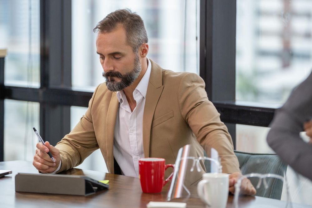 Man with beard with digital table at office desk