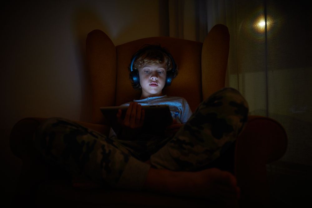 Boy playing on tablet at night
