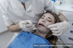 Dentist examining teenage girl's teeth in clinic 5rdyZb
