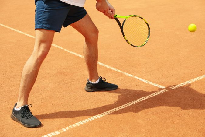 Young man playing tennis on clay court