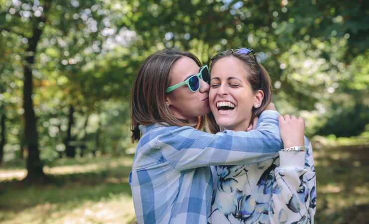 Woman kissing and embracing to female friend laughing