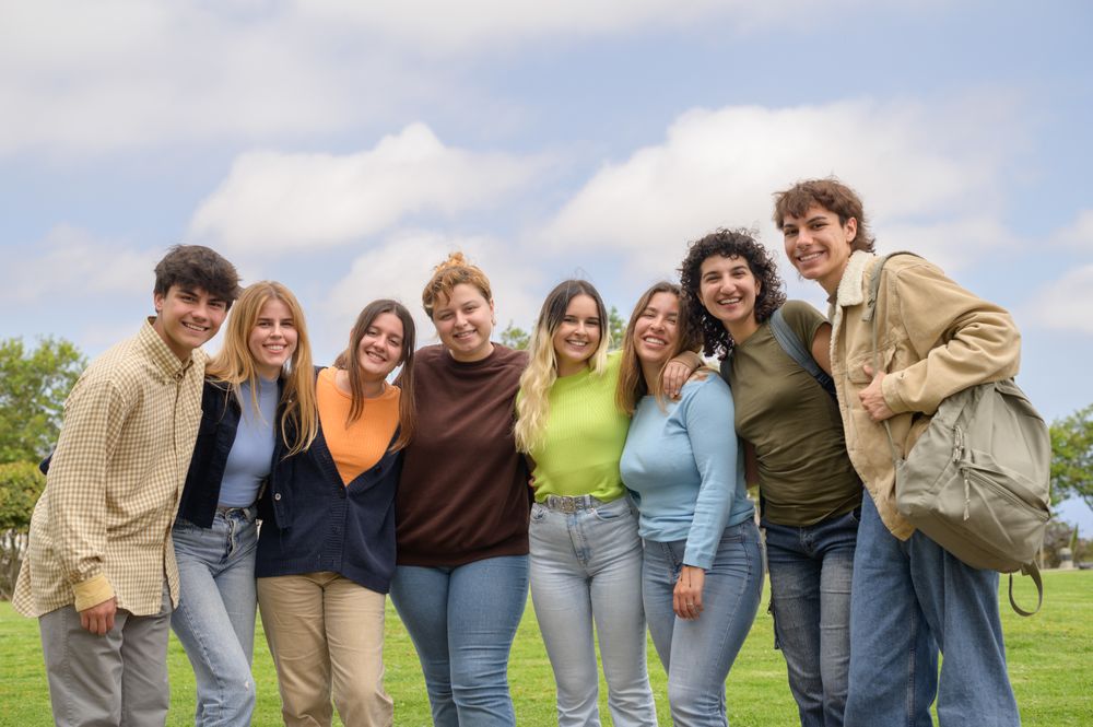 Happy multiethnic groupmates smiling and looking at camera in park