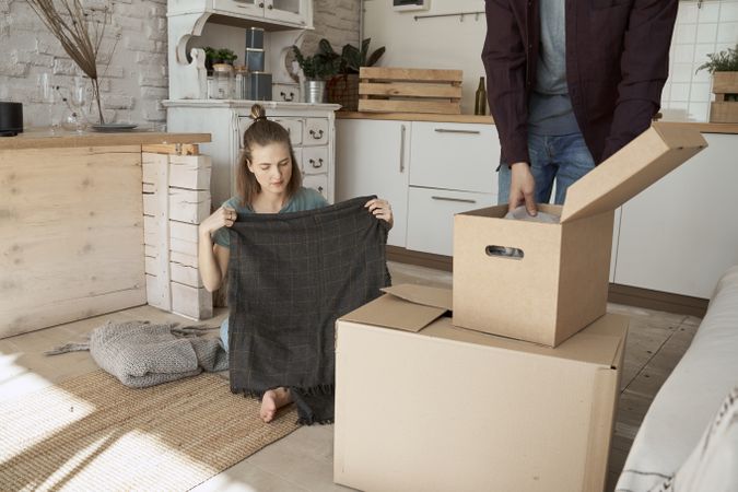 Cheerful couple unpacking boxes in light kitchen