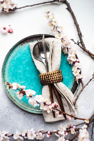 Table setting with delicate apricot blossom around elegant teal plates