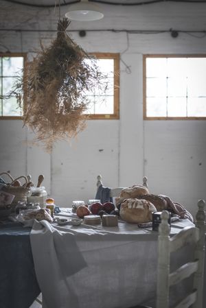 Fresh bread on served table and bunch of dry plant hanging on thread