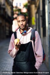Vertical shot of male on European street eating an apple 5l2oVb