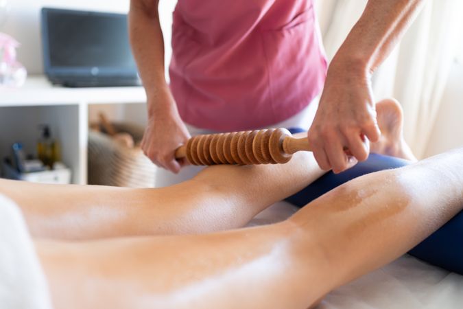 Massage therapist working on calves of woman in spa