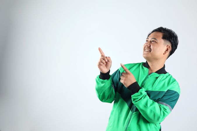 Asian Online Driver with Unifrom Jacket Pointing at Copy Space