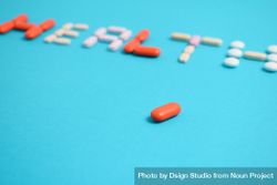Pills spelling the word "HEALTH" on blue background bxARov