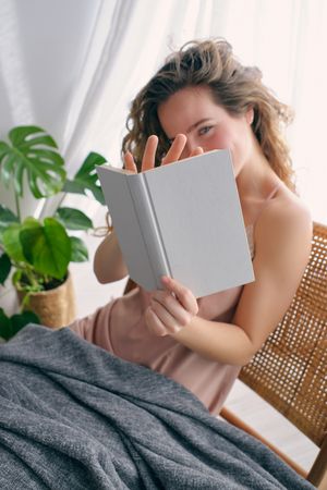 Young woman reading book on wicker chair