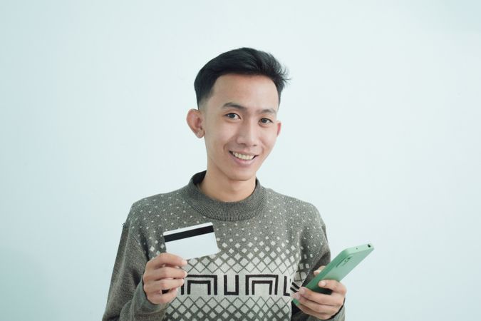 Happy businessman wear suit with t-shirt holding blank credit card in studio shoot