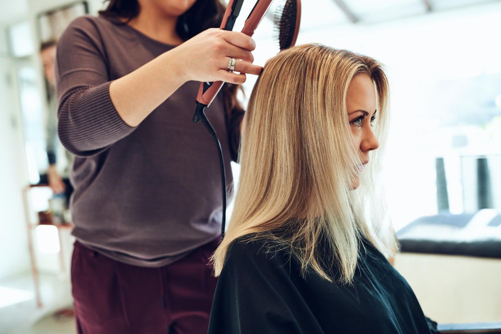 Close up of a woman sitting at a hair salon and getting her hair styled