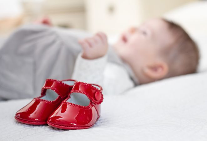 Baby red shoes and babe lying on the background