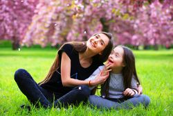 Playful siblings having fun at a park with flower petals falling from a tree