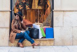 Content young woman in casual outfit resting on street after shopping