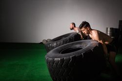 Men flipping big tires in gym