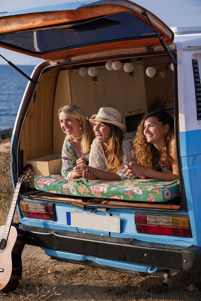 Pleasant women lying on trunk of bright minivan in sunny day