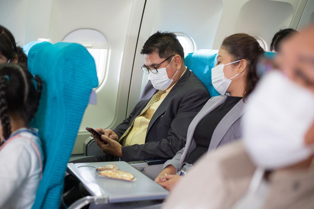 Male in business attire checking phone while sitting on flight