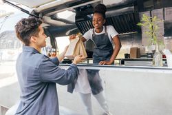 Male getting meal to go in paper bag from food truck vendor