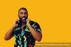 Black male in bold patterned shirt and headphones in yellow room 0W3910