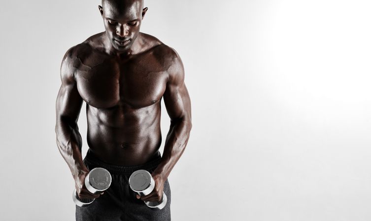 Fit Black male model with dumbbells over grey background